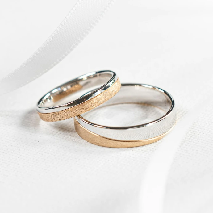 two wedding rings sitting on top of a white cloth
